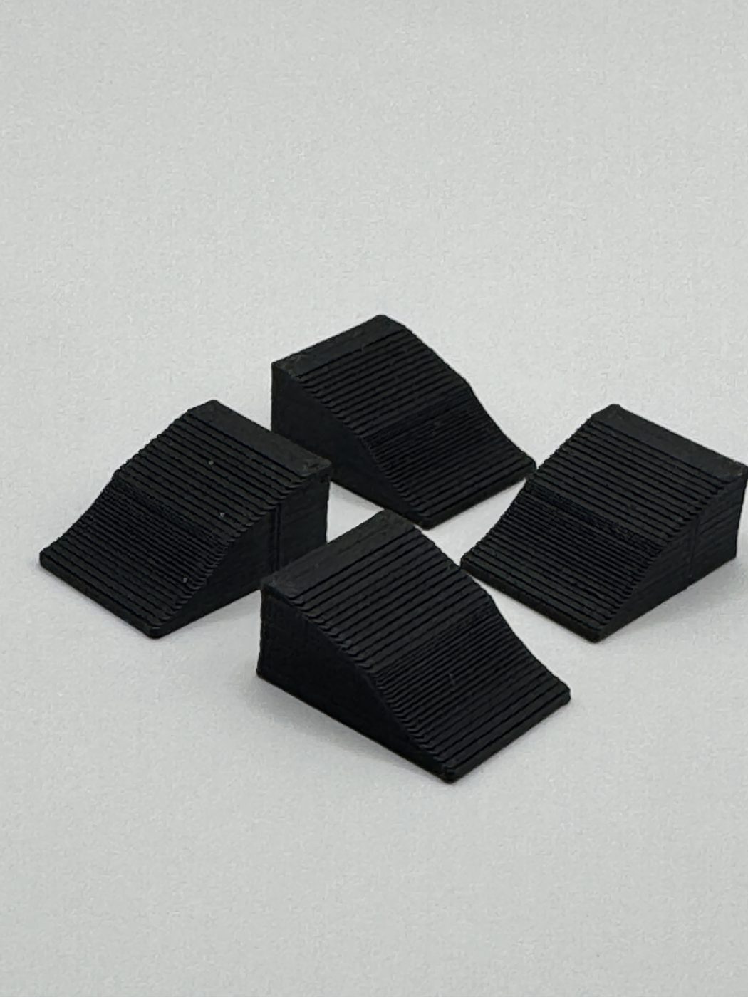 Four black scale wheel chocks on a white background