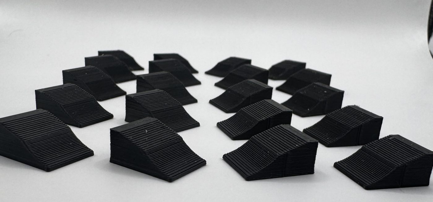 Twenty black 1:24 scale wheel chocks fanned out on a white background
